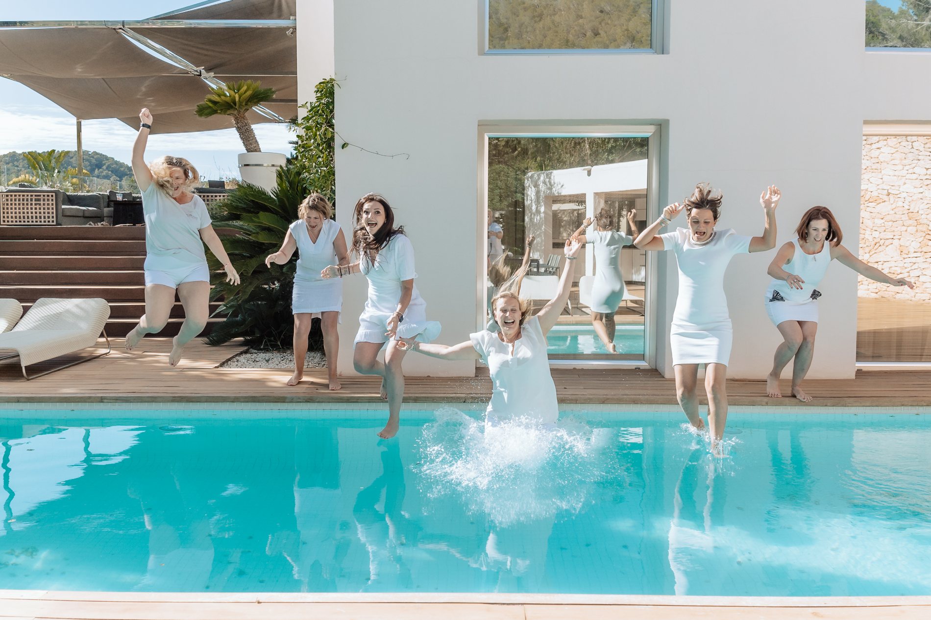 Frauen springen gemeinsam in den Villenpool